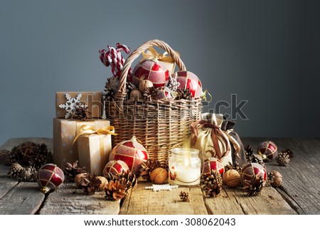 Christmas Composition with Gifts and Burning Candle. Basket, red balls, pine cones, snowflakes on Grey Background. Vintage style
