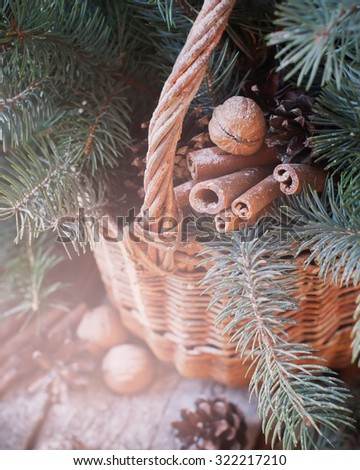 Natural Christmas Decor in a Basket. Nuts, Fir Tree, Cinnamon, Pine cones on Wooden Background. Light effect
