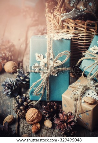 Boxes with Cozy Country Decor, Blue Paper, Snowflakes, Pine Cones, Walnuts, Almond, Linen Cord on Wooden Table. Toned with Light Shine Effect