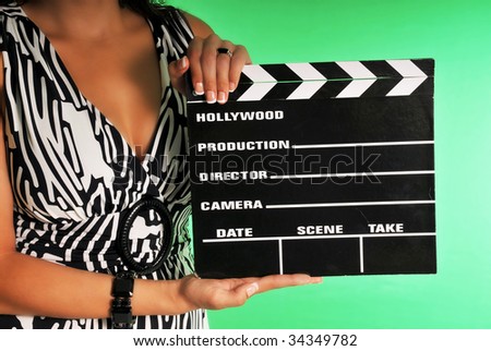 woman holding a movie clapper set against a chroma green screen