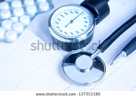 Stethoscope, blood pressure monitor, pills and pen on electrocardiogram chart. Medical concept for cardiology, examination, screening, blood pressure. Copy space.