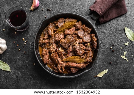 Meat Stew. Beef stewed in red wine sauce, top view, copy space. Roasted beef meat. Braised beef portion meat. Slow cooked meat in cast iron pan.