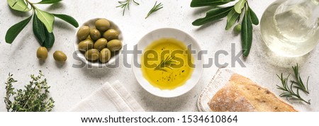Olive Oil. Organic olive oil  in bowl with green olives, herbs, spices and ciabatta bread on white background , banner, healthy mediterranean food concept.