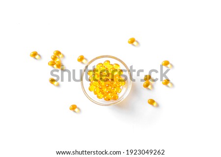 Oil filled capsules (softgel) of food supplements: fish oil, omega 3, omega 6, omega 9, vitamin A,  vitamin D3, vitamin E, evening primrose oil, borage oil. Yellow softgels on white,  copy space.