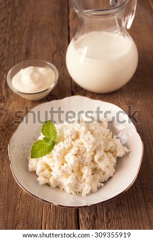 Organic cottage cheese and other dairy products (milk, sour cream) for breakfast on rustic wooden background