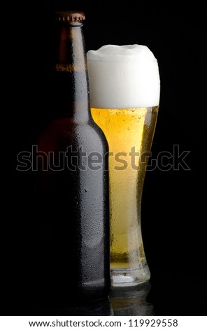 Beer bottle and glass of cold beer on black background
