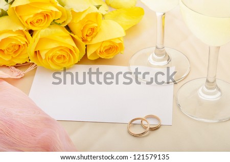 Blank sheet of paper for invitation with yellow roses, wine  and wedding rings