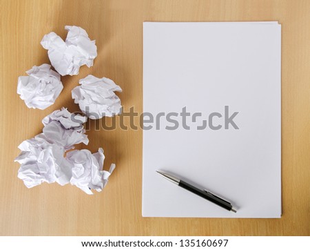 Crumpled paper balls and blank sheet of paper with pen