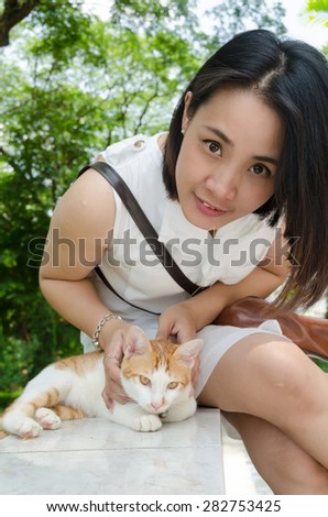Women play with a cat in green garden