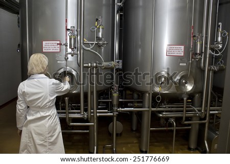 Kiev region, UKRAINE - 15 November 2014: Dairy baby food factory. Worker conducts quality control near the tank with milk