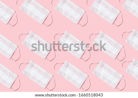 Many medical masks on the pink colored background to cover the mouth and nose for protection from virus and bacteria on a pink background. Epidemic concept. Regular pattern, flat lay.