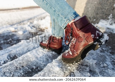 Winter is coming. Winter Female boots on rough slipper ice surface. A woman in vinous leather shoes descends the slippery ice ladder. Photo stock © 