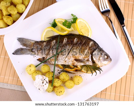 Grilled fish served with potatoes, sauce and lemon