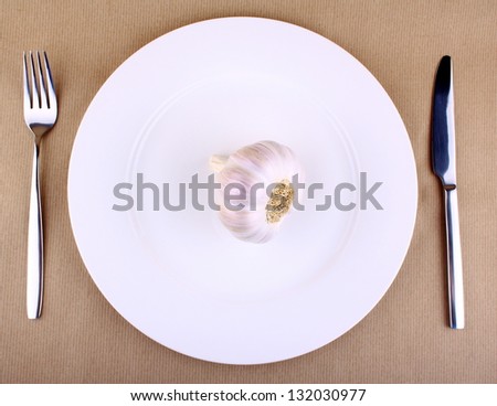 Healthy food - garlic on a white plate with fork and knife