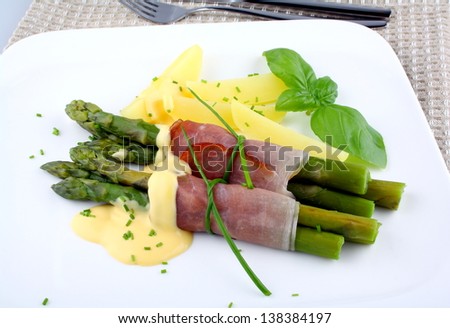 Green asparagus with potato, ham and sauce, close up
