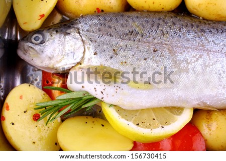 Marinated whole rainbow trout with red pepper, potato and lemon, top view