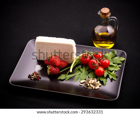 Ingredients for strawberry tomato salad with feta cheese, olive oil on black