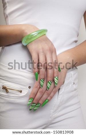 Woman hands with beautiful manicure with green nails and white blouse and pants around