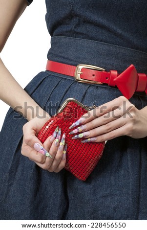 Hands of a young girl with a beautiful manicure in blue dress, red handbag and red belt. On white background.