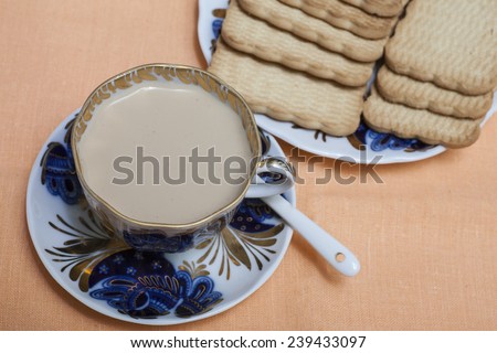 A cup of coffee milk and a plate of cookies on orange  background
