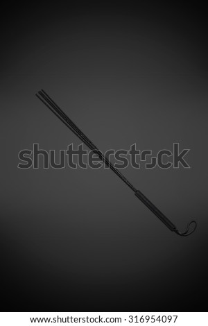 Black leather whip isolated on gray background
