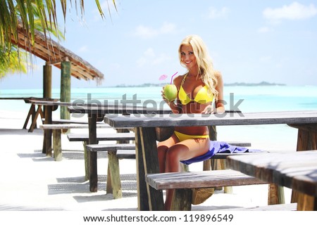 woman sitting in a tropical cafe on the background of a  palm trees and sky and sea