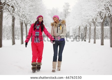two women walk by winter alley