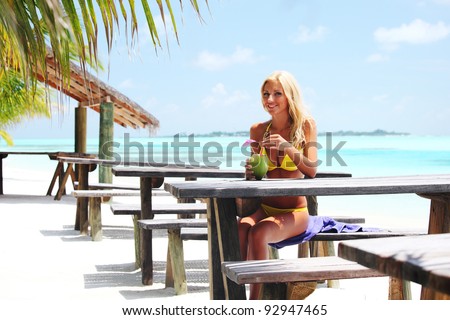 woman sitting in a tropical cafe on the background of a  palm trees and sky and sea