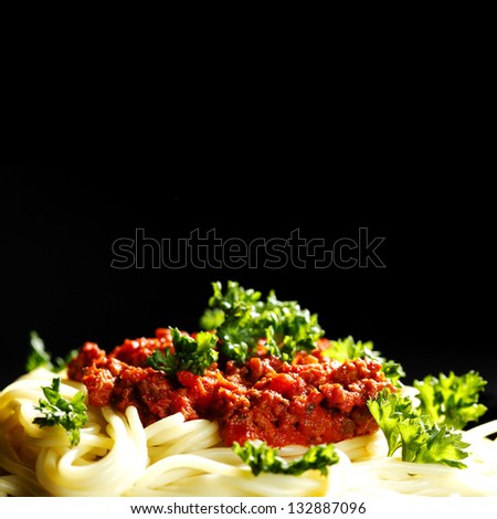 Spaghetti bolognese in black plate on dark background