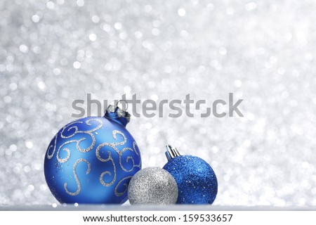 Blue shiny christmas balls on silver glitter background