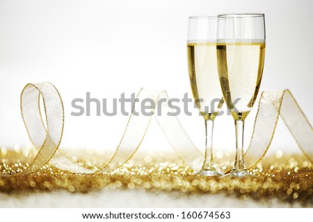 Two champagne flutes and decoration on gold shiny background