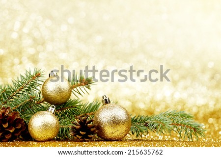 Christmas card with fir tree branch and decoration on golden glitter background