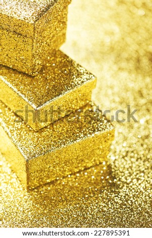 Stack of Gold decorative boxes with holiday gifts on abstract gold background