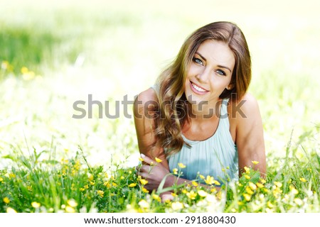beautiful young woman in blue dress lying on grass