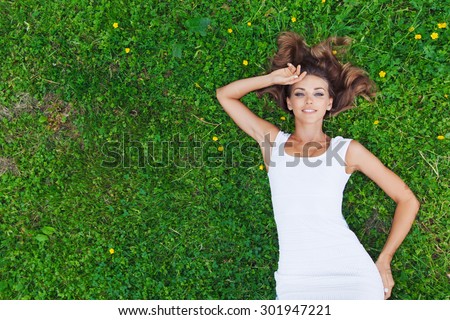 beautiful young woman in white dress lying on grass