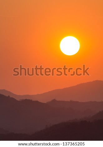 The picture shows a sunset with a silhouette view of hills. Orange color. Free area to type text.