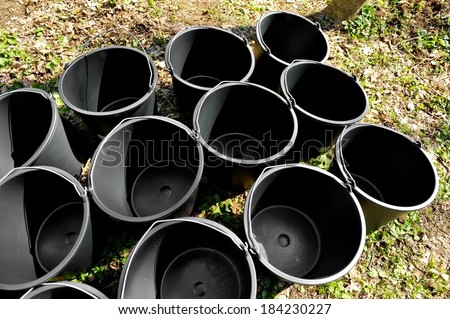 Several empty black gardening buckets on the ground