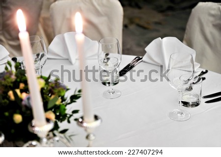 Candlestick with lit candles and floral arrangement on elegant dinner table