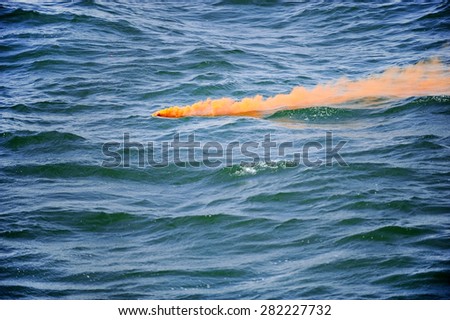 Orange smoke comes out from a flare fired during a safety demonstration drill on the sea