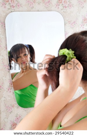 Pretty girl with pony-tails looks at the mirror