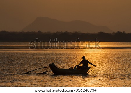 Arugam bay lagoon, Sri Lanka - July 20, 2014: Traditional fisherman boating in dugout canoe in Arugam bay lagoon in sunset time, Sri Lanka.