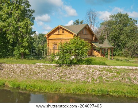 Landscape with a wooden small house in the forest by the river
