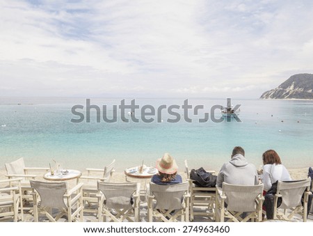 people sitting, drinking coffee and looking at the sea - Greek island background