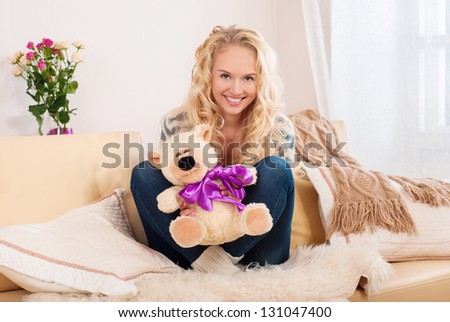 Portrait of a beautiful woman in the room. Woman resting at home. Hold in their hands a stuffed toy bear.
