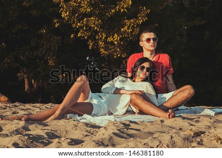 Beautiful young couple man and woman on the nature. Against the backdrop of sand and greenery. A man and woman in sunglasses on the banks of the river.
