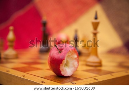 Chess pieces on the game board. Chess King. Pawns. The bitten apple. The game of chess. Autumn. Park. Apple is bitten. Autumn time enjoying the outdoors. Autumn day. Blanket and a bench outdoors.