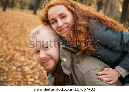 Happy people are jumping, having fun. Two young lovers and beautiful people for a walk in the park. The love story of two lovers. Reddish haired woman and a man with a beard. Autumn love Story two.