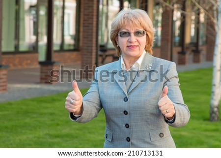 Adult business woman. Woman head small businesses. Portrait of a modern woman experienced leader. Adult woman of retirement age in the glasses. Happy smiling business woman with thumbs up gesture.