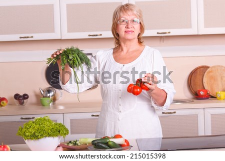 Adult woman working in the kitchen. Mom while she work something else. Mother prepares a salad. Cooking. Woman while preparing food in kitchen. Beautiful adult multiracial woman while making salad.