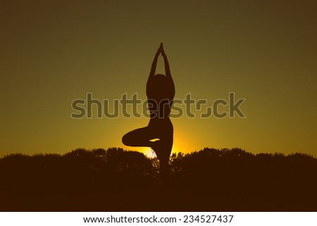 Silhouette of a woman at sunset or sunrise. Woman open arms under the sunrise. Woman doing yoga outdoors at sunset. Modern girl doing fitness exercises.